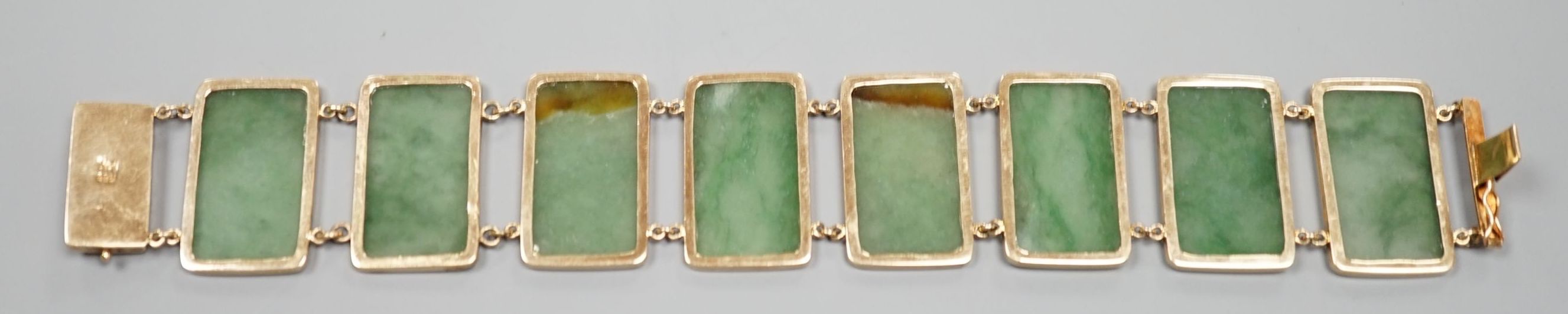 A 585 yellow metal and jade bracelet, set with eight rectangular panels, 18cm, gross weight 26.5 grams.